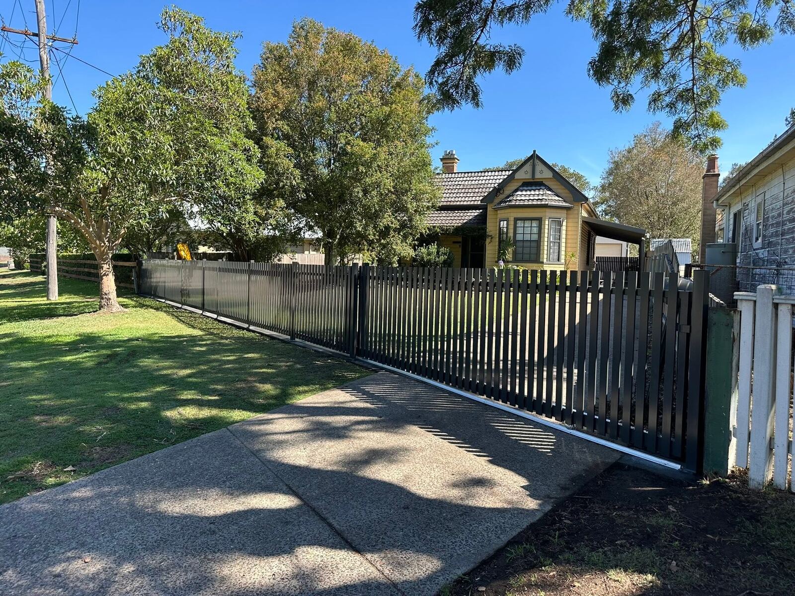 Black aluminium driveway gate at a heritage home