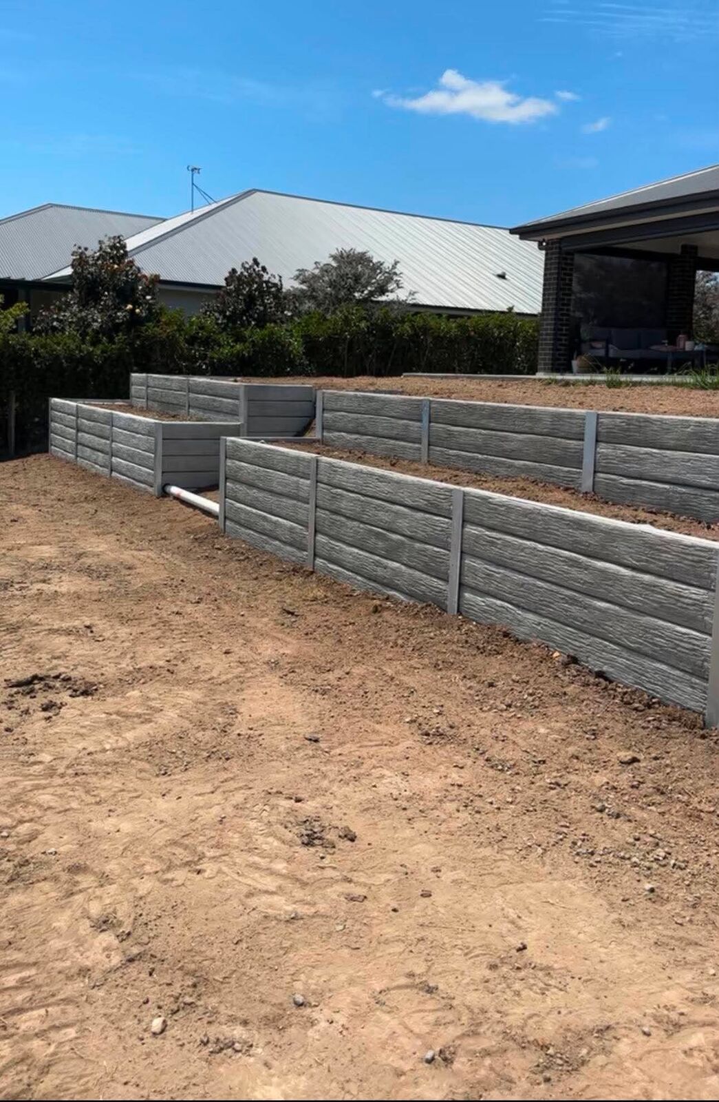 Stepped concrete sleeper retaining walls in a backyard