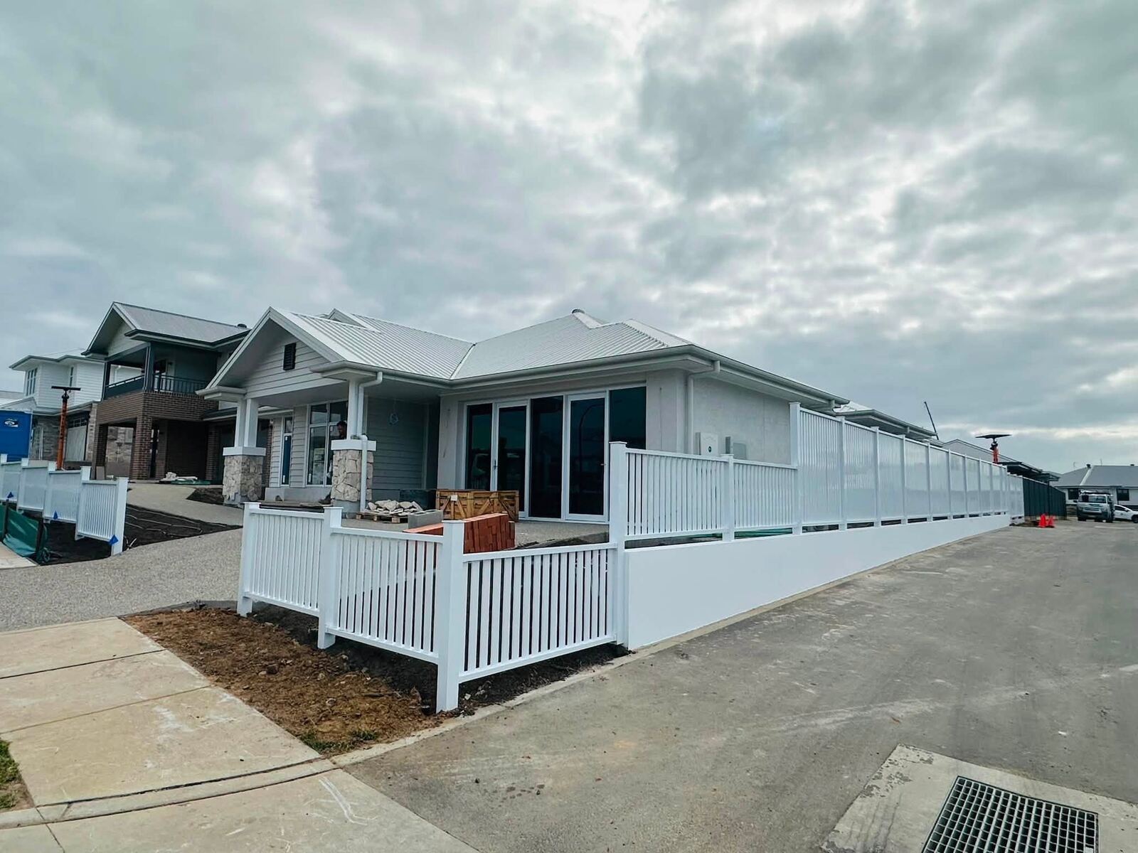 White picket and panel fence combination along a driveway