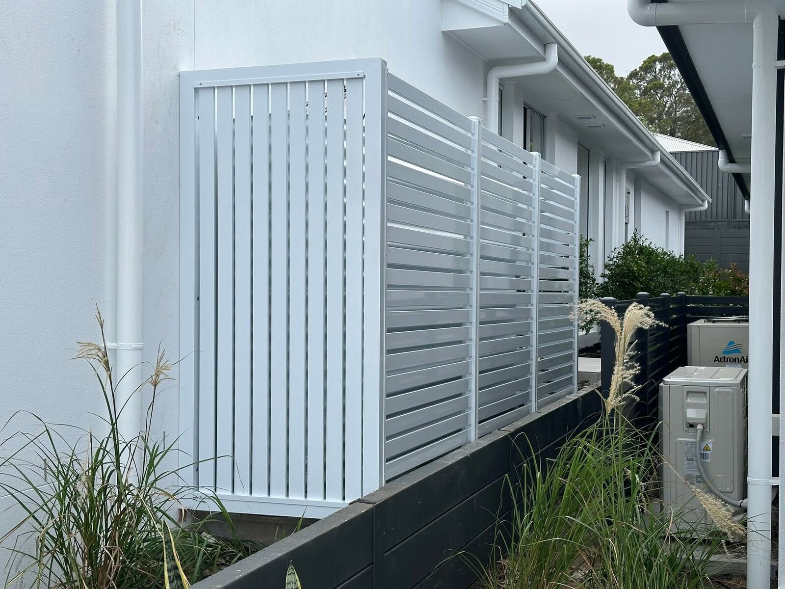 White slat privacy screen around air conditioning unit